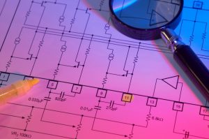 magnifying glass sitting on top of electrical blueprints