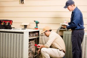 two technicians looking over outside air conditioning unit