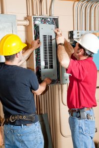 Two electricians working on electrical panel