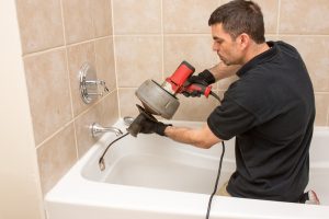 plumber-unclogging-drain-in-bathtub