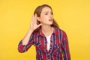 woman-holding-hand-to-ear-on-yellow-background