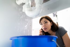 woman-looking-under-sink-at-leaking-pipe