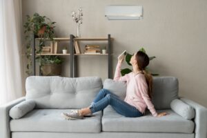 woman-sitting-on-couch-using-remote-to-turn-on-ductless-air-handler