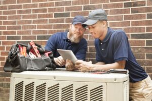two-technicians-working-on-outside-ac-unit
