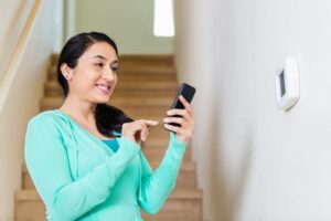woman-using-smartphone-to-adjust-thermostat