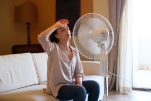 woman-trying-to-cool-off-in-home-sitting-in-front-of-fan