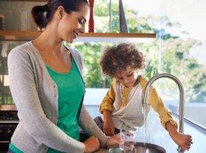 lady-getting-glass-of-water-in-kitchen-sink-for-child-sitting-on-counter