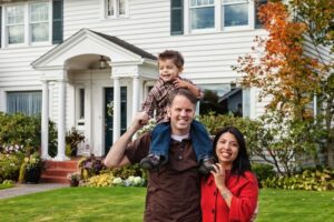 family-standing-in-front-of-older-home