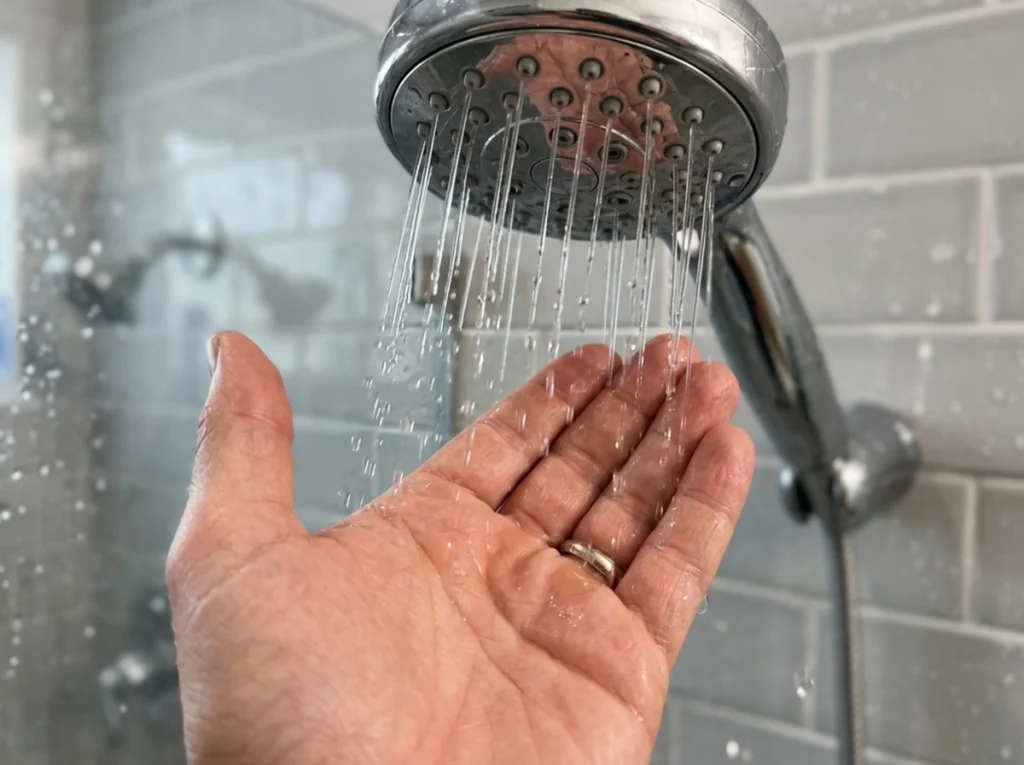 A hand feeling the low pressure in the shower.